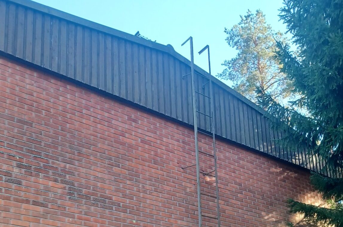 Tiilirivitalon seinätikkaat nousevat räystään yli peltikatolle.