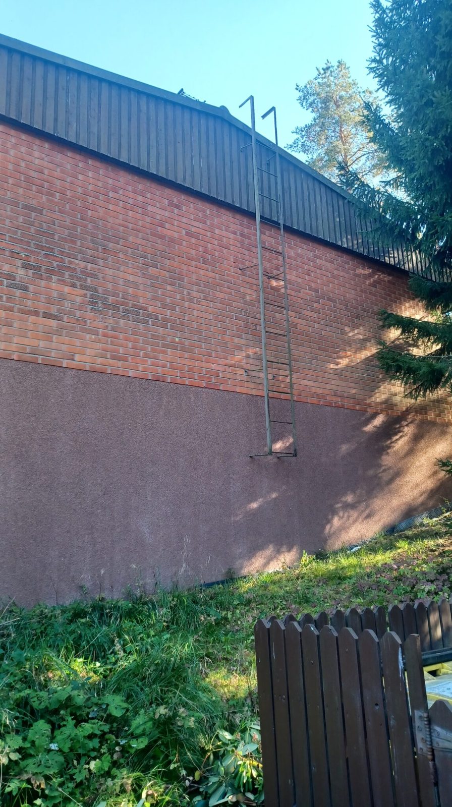 Tiilirivitalon päätyseinän korkeat seinätikkaat, jotka nousevat räystään yli katolle.